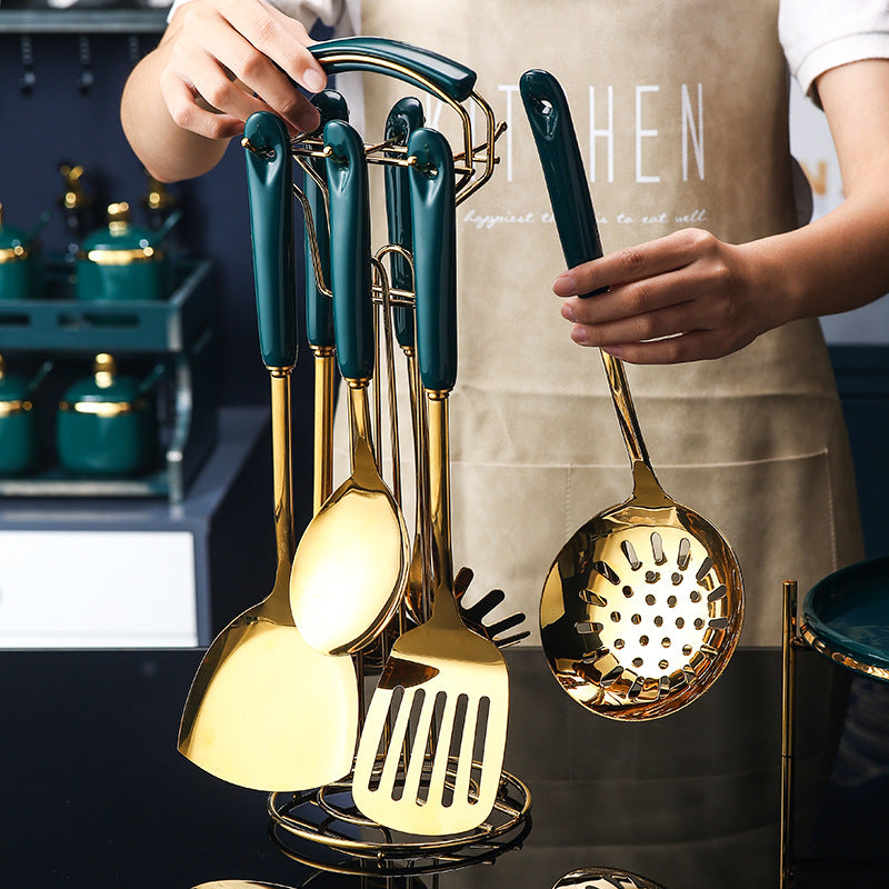 Set of gold and green kitchen utensils on a stand with a person wearing a beige apron.