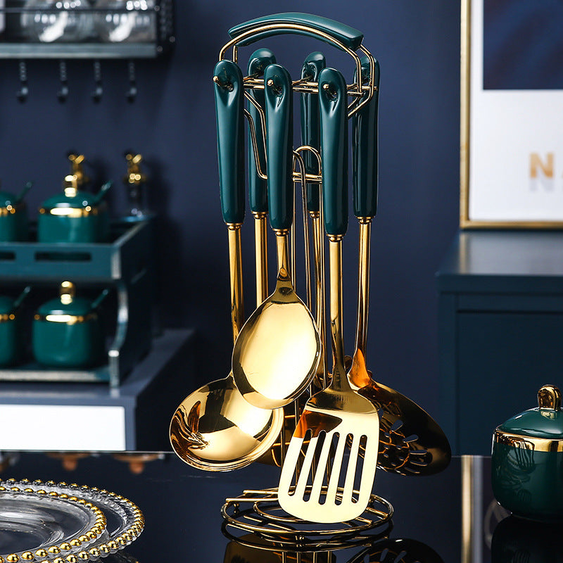 Set of gold and green kitchen utensils on a dark surface with a blurred kitchen background.